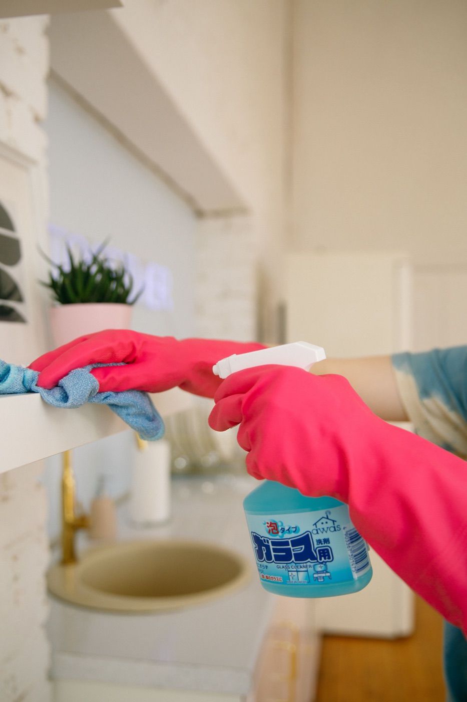 Cleaner spraying and wiping a glass surface with a microfibre cloth