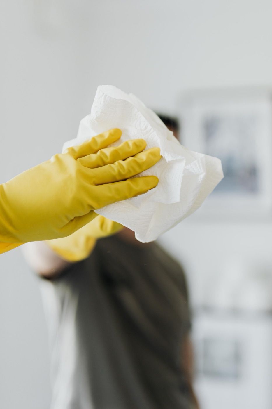 Gloved hand wiping down a clean white surface